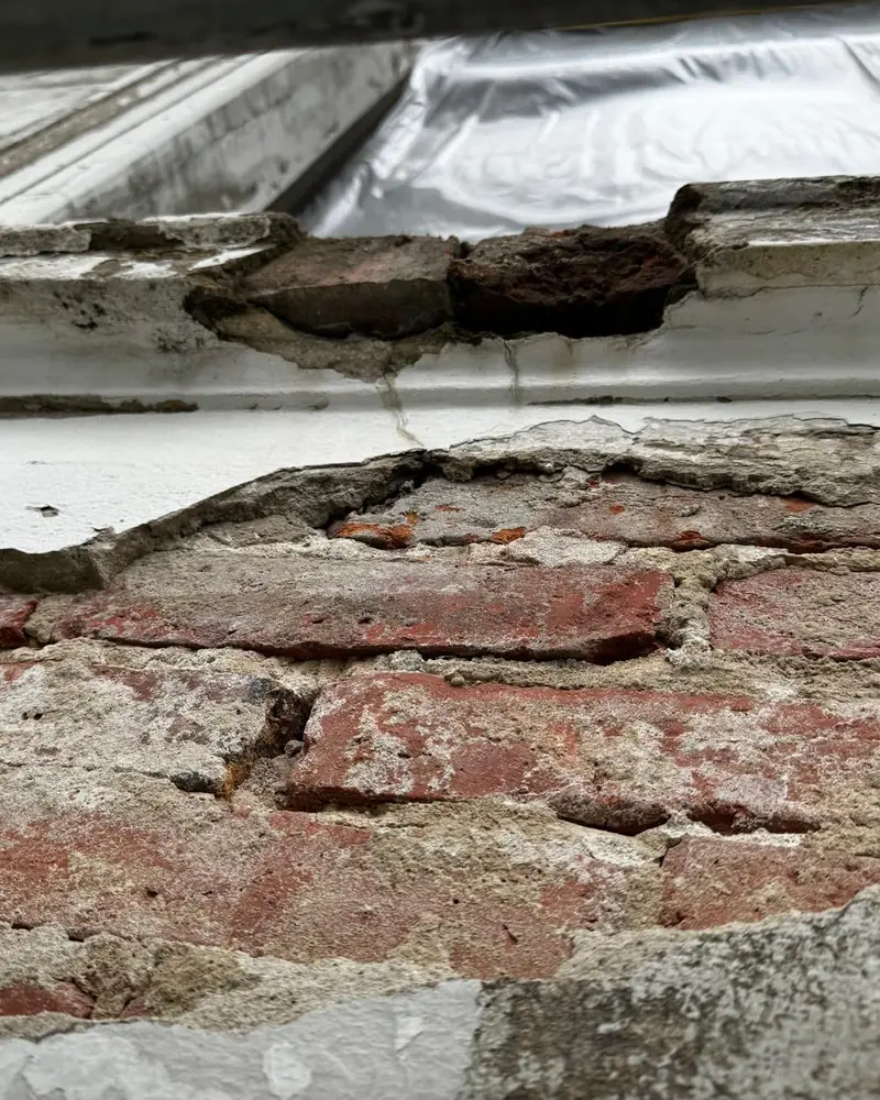 Brüstung unter dem Fenster: Putzschale gelöst, Ziegel und Mörtel zerbröselt